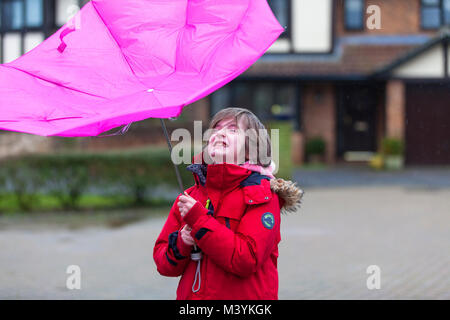 Ashford, Kent, Großbritannien. 13 Feb, 2018. Ein 8 Jahre altes Kind in eine rote Jacke spielt im Regen mit einem rosa Regenschirm, der sich von innen nach aussen gefaltet hat, gekleidet. Photo Credit: PAL Bilder/Alamy leben Nachrichten Stockfoto