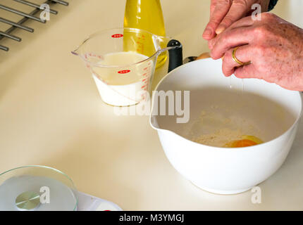 Mann schlagen Mischung mit Schneebesen Pfannkuchenteig für Faschingsdienstag mit Mehl, Milch, Eier und Öl in einer Küche zu Hause Stockfoto