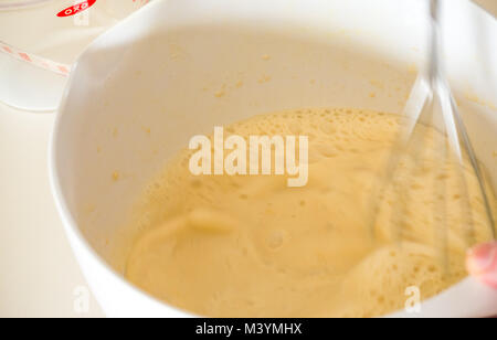 Mischung schlagen mit Schneebesen Pfannkuchenteig für Faschingsdienstag mit Mehl, Milch, Eier und Öl in einer Küche zu Hause Stockfoto