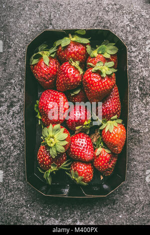 Erdbeeren in Papier Kisten Kasten auf grauem Granit Tabelle, Ansicht von oben. Gesunde Diät und Antioxidans Bio Früchte Stockfoto