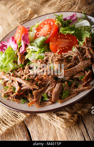 Langsam Rindfleisch mit frischem Gemüse Salat schließen gekocht - bis auf einen Teller auf dem Tisch. Vertikale Stockfoto