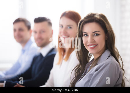 Portrait der junge lächelnde Geschäftsfrau mit Ihren Kollegen im Büro Stockfoto