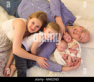 Glückliche Eltern posiert mit ihren Neugeborenen eineiige Zwillinge und Kleinkind Bruder Stockfoto