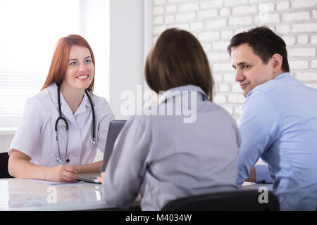 Ansicht der Rückseite ein Paar sitzen Vor der weiblichen Arzt Stockfoto