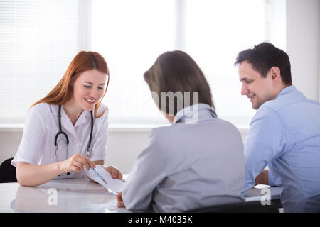 Junge weibliche Arzt, der das Rezept Papier zum Patienten in der Klinik Stockfoto