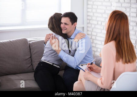 Psychologe an glückliches junges Paar einander umarmen Suchen Stockfoto