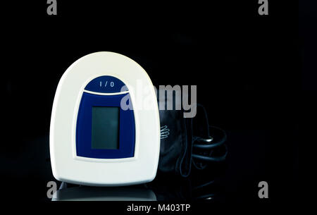 Blau-weißes digitales Blutdruckmessgerät mit breiter Manschette auf dunklem Hintergrund. Gesundheit checkup Konzept Stockfoto