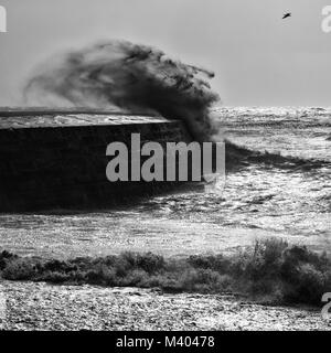 Lyme Regis an einem stürmischen Tag in Bkack und Weiß, Wellen über den Cobb. Stockfoto