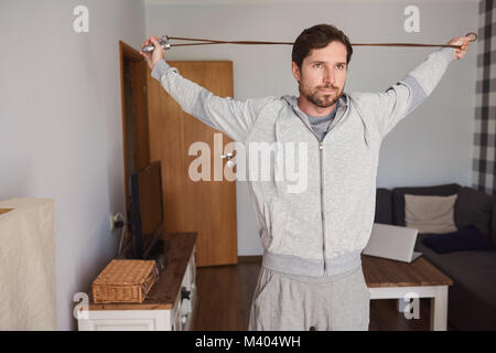 Passen junge Mann in Sportkleidung Ausübung in seinem Wohnzimmer Stockfoto