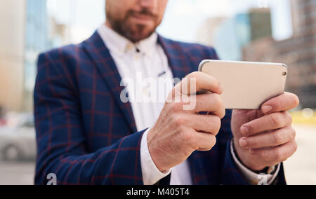 Zugeschnittenes Bild der Hände der Geschäftsmann mit seinem Smartphone Stockfoto
