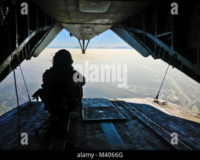 Sgt. Adam Collins, ein CH-53E Crew Chief mit Marine schweren Helikopter Squadron (HMH) 465, Scans der Bereich unterhalb zwischen springt während des Fluges und Fallschirm Operationen mit 1. Marine Reconnaissance Bataillon des Marine Corps Base Camp Pendleton, Calif., Feb 6. Während der Fallschirm und Flugbetrieb, die bodenkampf Element und die Air Combat Element arbeiten zusammen, um die Sicherheit und Leistung während der Ausbildung zu gewährleisten. (U.S. Marine Corps Foto von Sgt. David Bickel/Freigegeben) Stockfoto