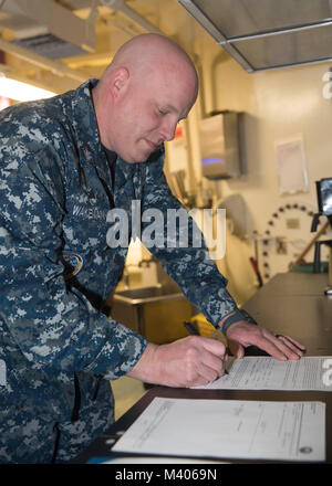 NORFOLK, Virginia (Feb. 6, 2018) - Aviation Machinist Mate 1. Klasse Justin Wakeman, von Bradford, New York, zu USS Gerald R. Ford's (CVN 78) Aviation intermediate maintenance Abteilung zugewiesen, Zeichen seiner reenlistment Dokumente während seiner reenlistment Zeremonie. (U.S. Marine Foto von Mass Communication Specialist 3. Klasse Sean Elliott) Stockfoto