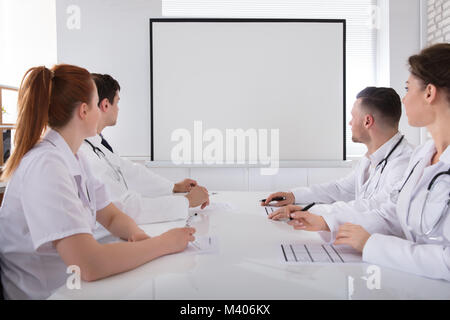 Männliche und Weibliche Ärzte am weißen Brett Im Treffen Stockfoto