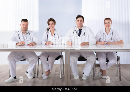 Porträt eines lächelnden professionellen Ärzten am Schreibtisch in einer Reihe sitzen Stockfoto