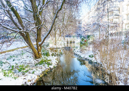 Kleiner Fluss mit mini Pont im Park, Outdoor in Paris, Frankreich, bei Schneefall im Winter. Am Morgen mit dem Sonnenaufgang das Licht genommen. Smart Concept Stockfoto