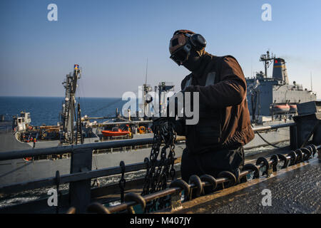 180208-N-VN 584-1449 arabischen Golf (Feb. 8, 2018) Aviation Ordnanceman Airman Jake Medill, zugeordnet zu den Cougars von Electronic Attack Squadron (VAQ) 139, drehbarer Ketten auf dem Flugdeck der Flugzeugträger USS Theodore Roosevelt (CVN 71) während einer Auffüllung-auf-See mit der Flotte Auffüllung öler USNS Guadalupe (T-AO-200). Theodore Roosevelt und ihre Carrier strike Group werden in den USA 5 Flotte Bereich für Maßnahmen zur Erhöhung der Sicherheit im Seeverkehr im Einsatz Verbündeten und Partnern zu beruhigen und der Freiheit der Schiffahrt und des freien Handels in der Region erhalten. (U.S. Stockfoto