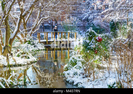 Kleiner Fluss mit mini Pont im Park, Outdoor in Paris, Frankreich, bei Schneefall im Winter. Am Morgen mit dem Sonnenaufgang das Licht genommen. Smart Concept Stockfoto