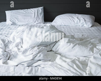 Unordentliche weiße Bettwäsche Bettwäsche und Kissen im Schlafzimmer Hintergrund, Ungemacht unordentliche Bett nach Komfort schlafen Konzept Stockfoto