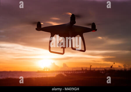 Silhouette von Flying drone im Sonnenuntergang die gedämpfte Beleuchtung. Stockfoto