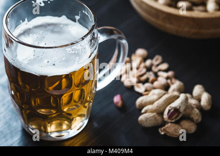 Glas Bier und Erdnüsse auf dem dunklen Hintergrund Stockfoto