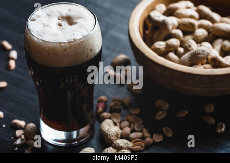 Glas Bier und Erdnüsse auf dem dunklen Hintergrund Stockfoto