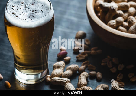 Glas Bier und Erdnüsse auf dem dunklen Hintergrund Stockfoto