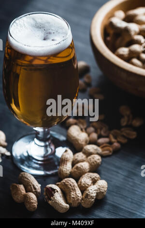 Glas Bier und Erdnüsse auf dem dunklen Hintergrund Stockfoto