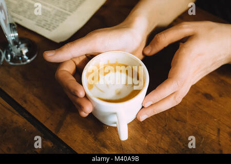 Mädchen, dass eine heiße Tasse Kaffee auf dem Tisch Stockfoto