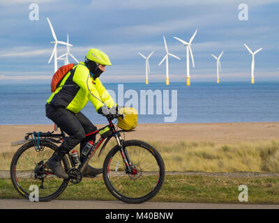 Ein Mann, der auf einem off road Sport Sport Fahrrad vor der Redcar Windfarm an Teesmouth Stockfoto