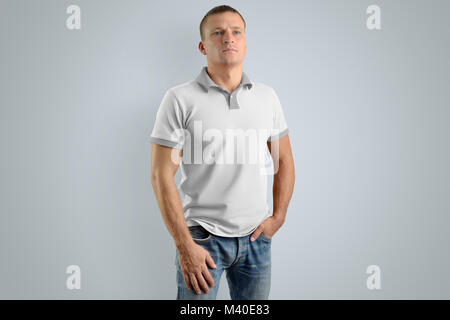 Stilvolle Mann in das leere Polo Shirt und Jeans auf den grauen Hintergrund isoliert, Vorderansicht. Mockup für Ihr Design. Stockfoto