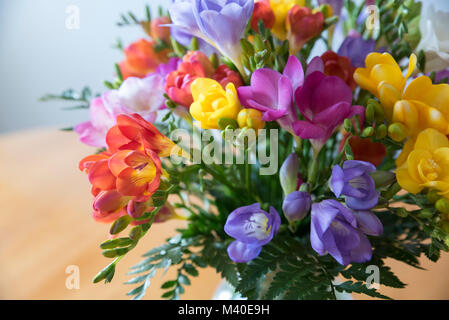 Bunter Blumenstrauß in einer Glasschale auf einem Holztisch Stockfoto