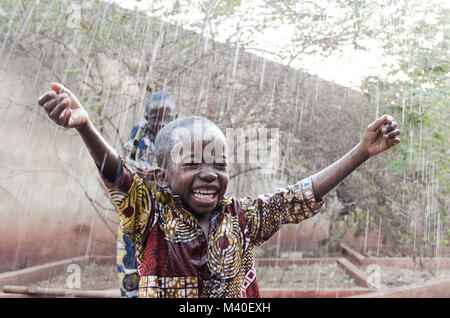 Paar afrikanischen schwarzen Kinder spielen unter dem Regen. Bruderschaft Symbol, Wasser für Afrika. Candid editorial erschossen in den Straßen von Bamako, Mali. Stockfoto