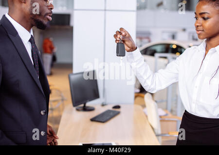 Absatzlage im Autohaus, junge afrikanische Paar erhält der Schlüssel für neue Pkw Stockfoto