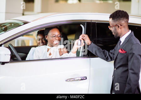 Absatzlage im Autohaus, junge afrikanische Paar erhält der Schlüssel für neue Pkw Stockfoto