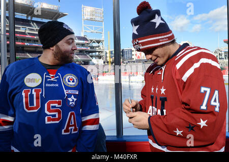 Washington Capitals nach vorne John Carlson Zeichen einen Puck für Michael Kain der USA Krieger verwundete Veteranen Team während eines Medien Tag für den Winter Classic 2015 Hockey bei Nationals Park in Washington, D.C., 31. Dez., 2014. Die National Hockey League waren die verletzten Veteranen Hockey Club in Medien Tag zusammen mit den Chicago Blackhawks und Washington Capitals. (DoD Nachrichten Foto durch EJ Hersom) 141231 - D-DB 155-002 von DoD News Fotos Stockfoto