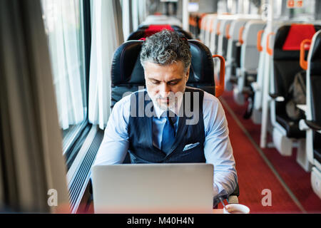 Reifen Geschäftsmann mit Laptop, der mit dem Zug reist. Stockfoto