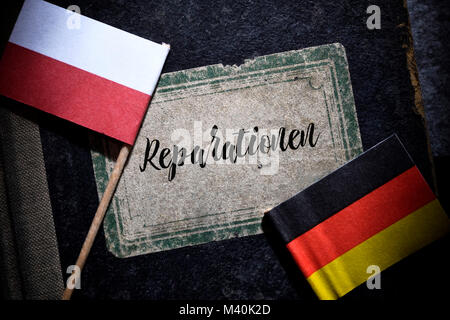 Flaggen von Deutschland und Polen und buchen Sie mit der Aufschrift Reparationen, Fahnen von Deutschland und Polen und Buch mit der Aufschrift Reparationen Stockfoto