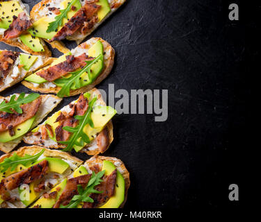 Avocado Sandwich auf hausgemachten Ciabatta Brot mit frischen in Scheiben geschnittenen Avocados und gebratenen Speck von oben. Top Bild anzeigen. Copyspace für Ihren Text Stockfoto