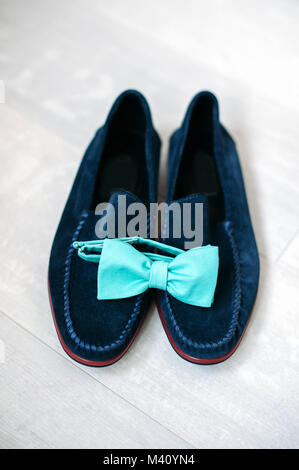 Türkis Bow Tie liegt auf der Blue suede shoes auf weißem Hintergrund Holz, Männer Zubehör. Stockfoto