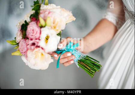 Braut holding Brautstrauß in der Hand. Weiß und rosa Blüten mit blauer Schleife. Bräute Maniküre mit einem Herzen Close-up Stockfoto