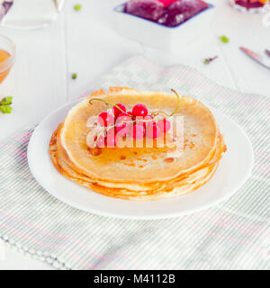 Dünne Pfannkuchen mit rote Johannisbeere Beeren auf dem serviert weiße Holztisch. Im rustikalen Stil. Traditionelle für den Russischen fastnachtswoche Maslenitsa (). Selectiv Stockfoto