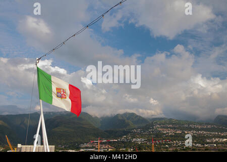 Italienische Flagge mit Maltesischen symbolics gegen den Hintergrund der hügeliges Gelände. Boeuf - Mort, Reunion Stockfoto