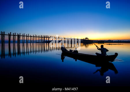 U-Bein Brücke aus Teakholz, eine alte Brücke, ist Spiegelung auf Taungthaman See vor Sonnenaufgang, ein Fischer Überfahrt mit dem Boot Stockfoto