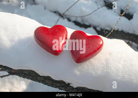 Zwei rot bemalte Holzherdfiguren auf dem Schnee Stockfoto
