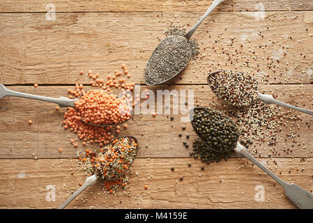 Alte Löffel mit Leguminosen, Linsen, Quinoa und Chia Samen lieing auf Holz alte Tabelle Stockfoto
