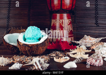 Blue Ice Cream Coconut Schüssel in der Nähe von Sand, Muscheln, Seesterne. Stockfoto