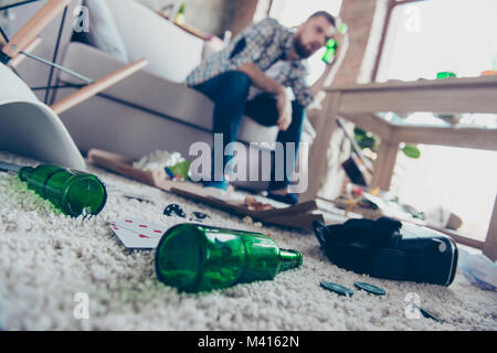 Konzept der Kopfschmerzen nach global Party. In der Nähe von Low-winkel Foto von Leer grün transparent Bierflaschen liegen auf Windel beigefarbenen Teppich, Kerl mit Stockfoto