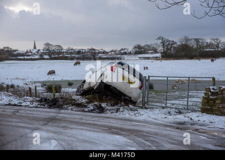 Eine weiße Nissan Note Auto rutschte von der Straße in eine Hecke auf einer vereisten Straße, Longridge, Preston, Lancashire am 12 Februar, 2018. Stockfoto