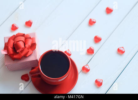 Rote Kaffeetasse und Geschenkbox auf hölzernen Tisch Stockfoto