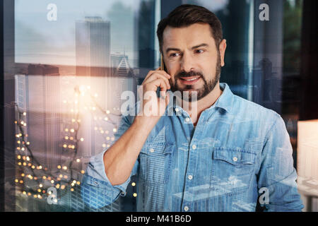 Fröhliche bärtiger Mann lächelnd, während Sie einen angenehmen Telefon sprechen Stockfoto